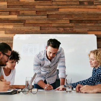 Group of colleagues having a brainstorming session in conference room. Young man explaining business plans to coworkers during meeting in boardroom.