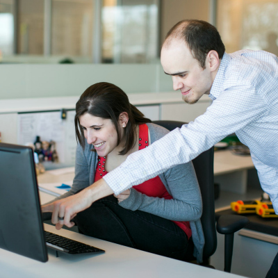 Two Brooks Bell employees talk at a computer